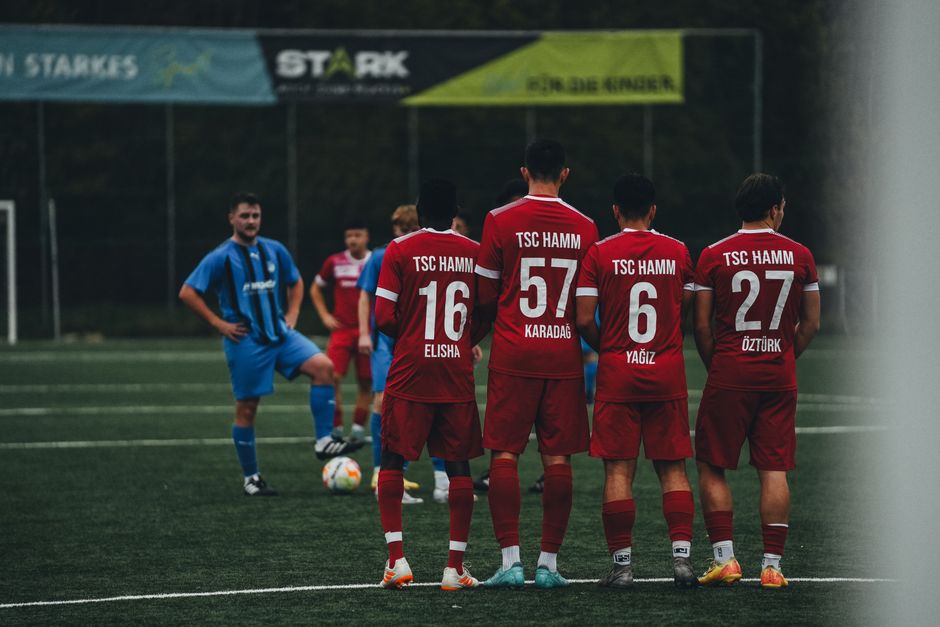 Soccer players forming a wall for a free kick during a match on a grassy field.